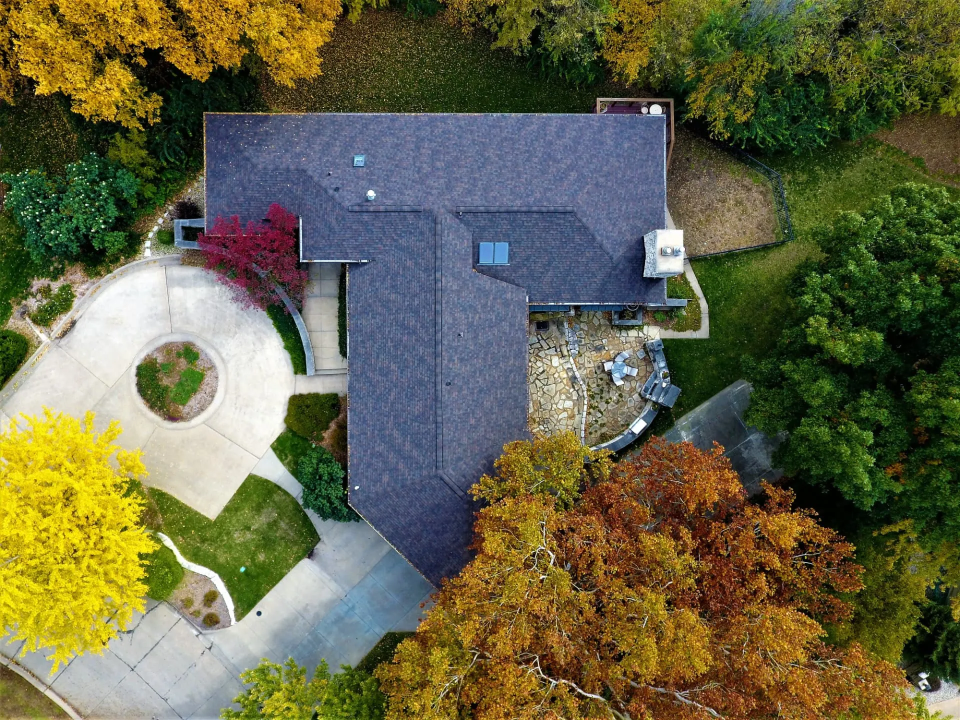 Aerial view of a completed architectural shingle roof replacement surrounded by vibrant autumn trees in Manhattan, Kansas