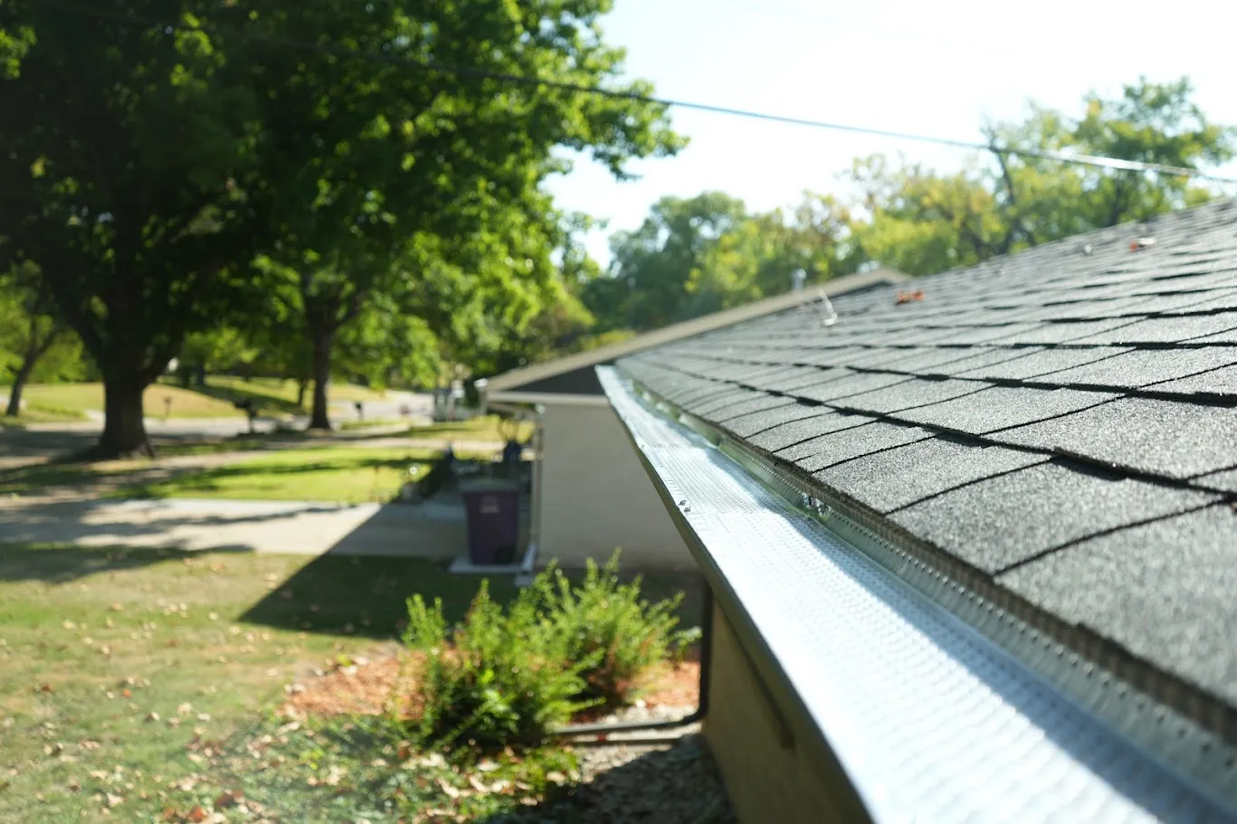 New aluminum gutter protection installed along an architectural shingle roof