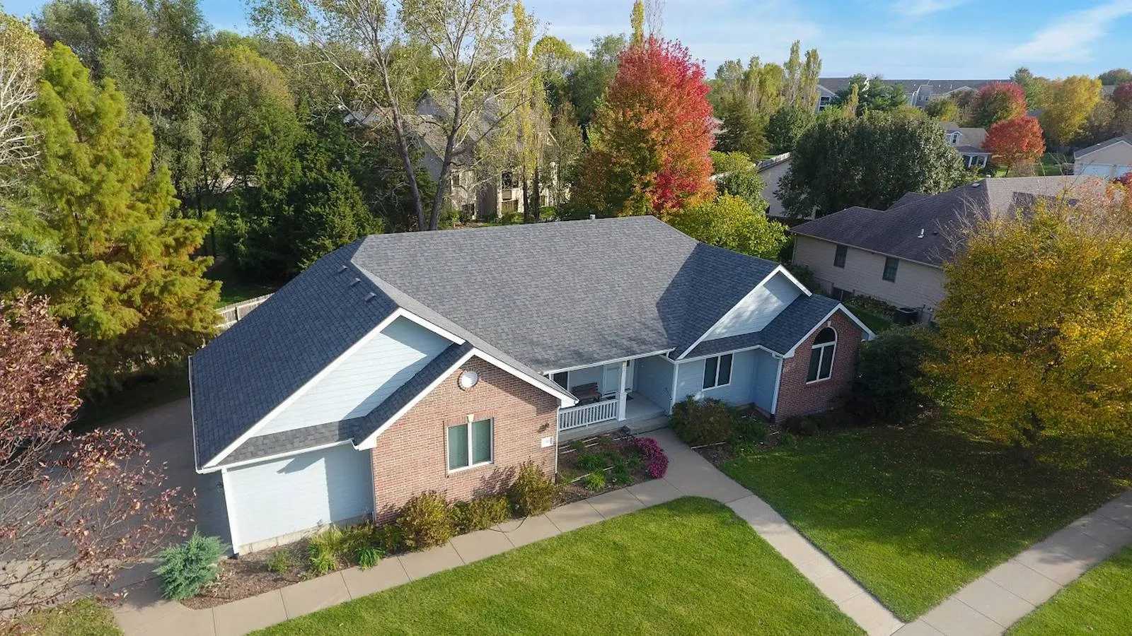 Brick ranch home in Baldwin City, Kansas with a new gray architectural shingle roof and fall trees