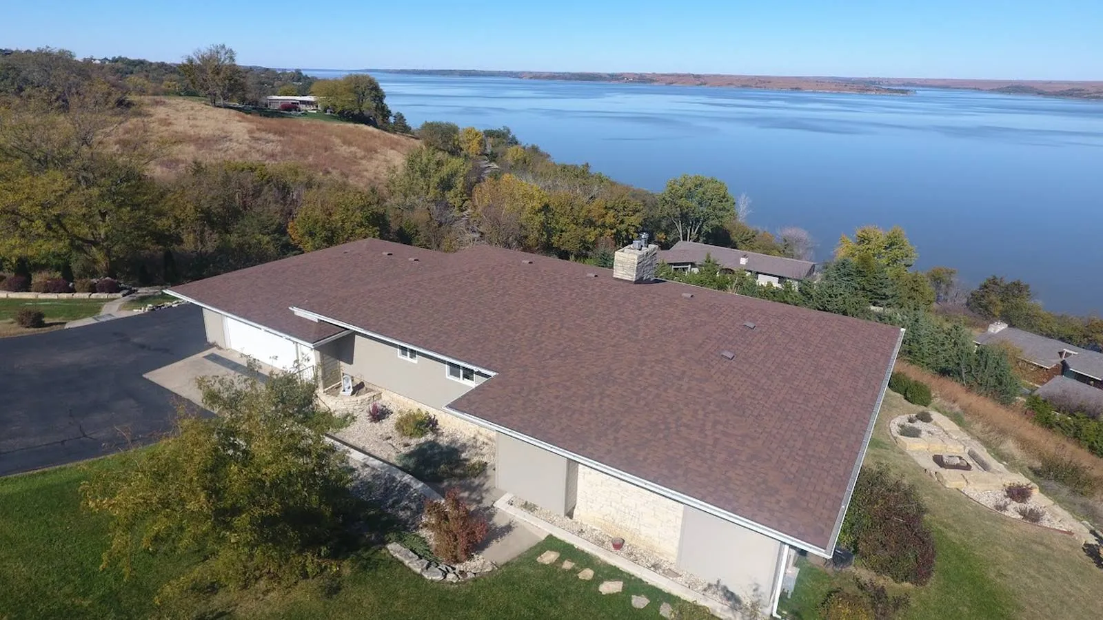 Lakeside home near Burlington, Kansas with a new brown architectural shingle roof overlooking the water