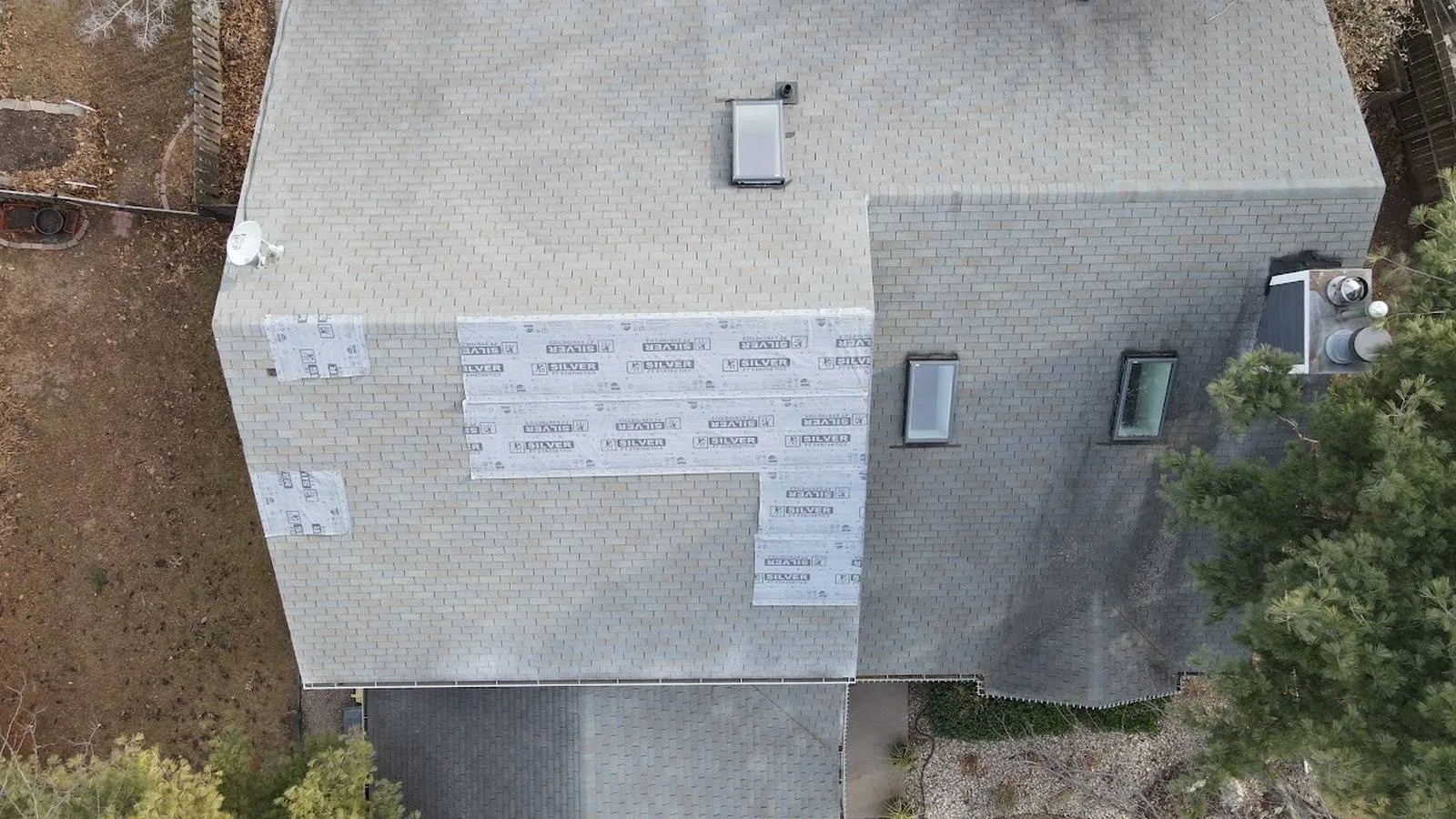 Overhead view of a storm damaged roof protected with synthetic underlayment during repair, serving Commerce City, Colorado