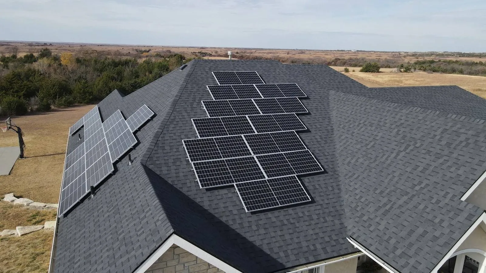 Ranch home with a new shingle roof and seamless gutters beside wheat fields near Ellsworth, Kansas