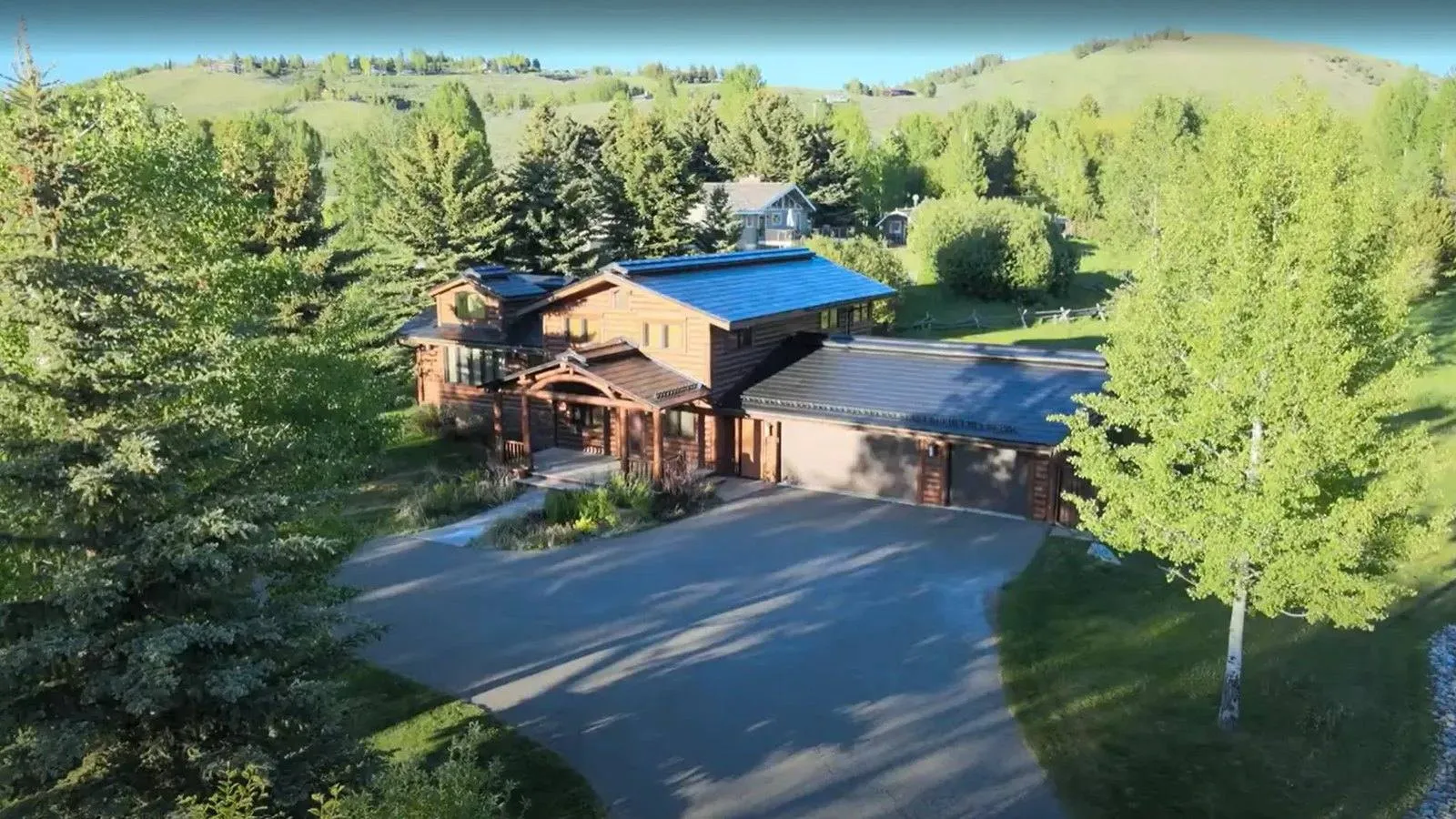Aerial view of a log home near Golden, Colorado with a dark solar roof and green foothills behind it