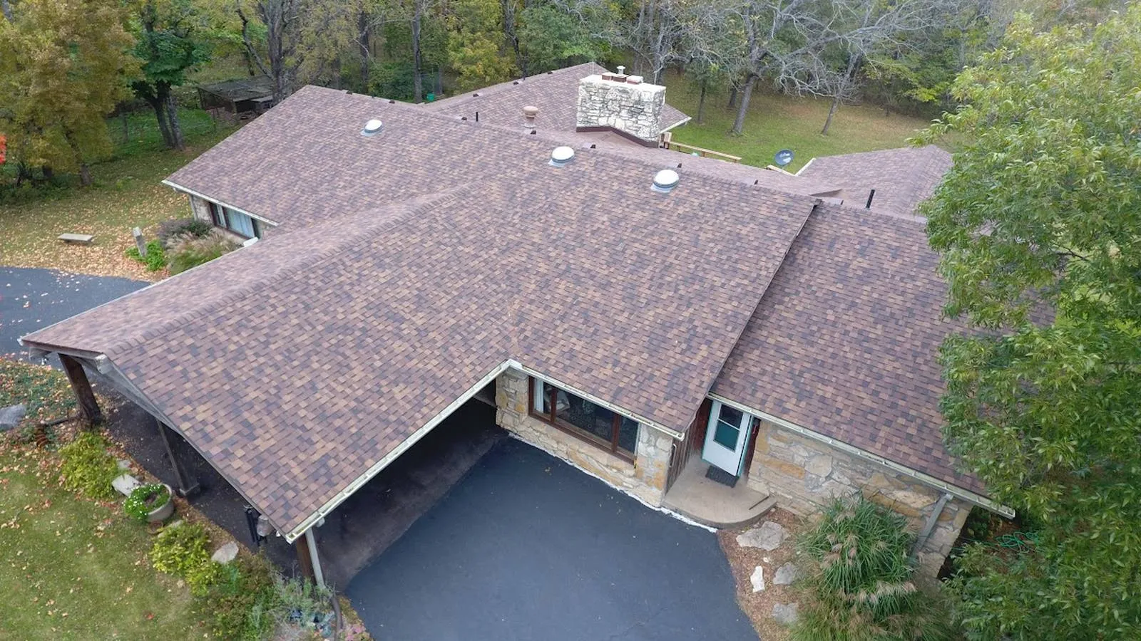 Stone ranch home in Grandview, Missouri with a new brown architectural shingle roof and wooded backyard
