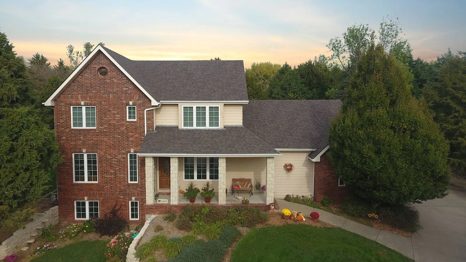 Brick two story Gretna, Nebraska home with a new architectural shingle roof at sunset