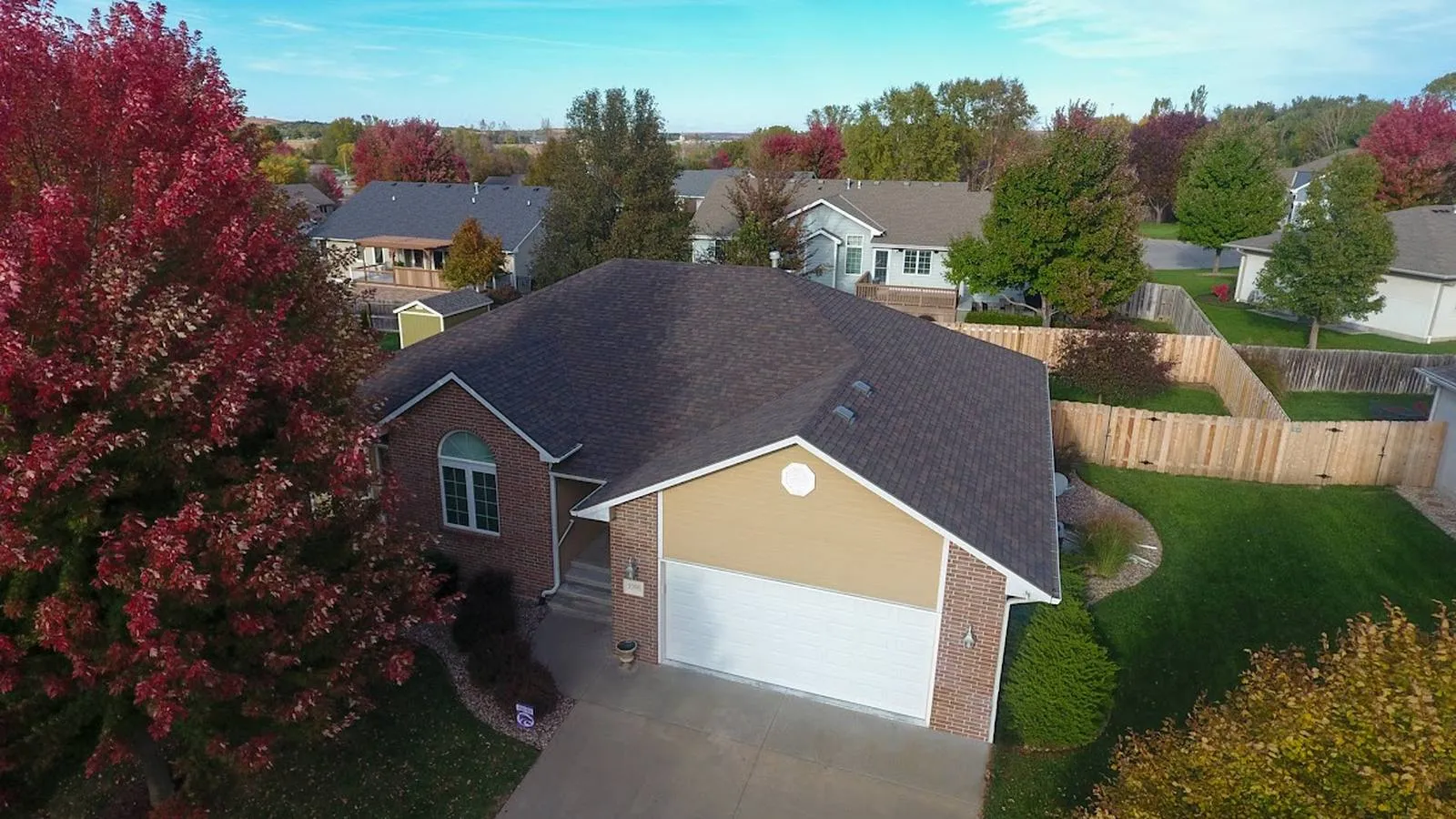 Brick ranch home in Hickman, Nebraska with a new brown architectural shingle roof and fall trees