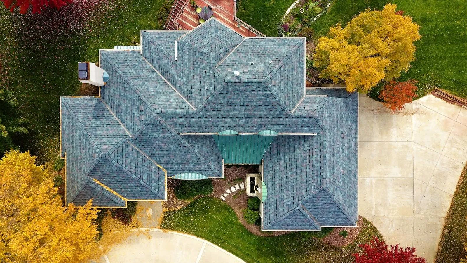Overhead view of a Hillsboro, Kansas home with a new blue toned shingle roof among fall trees