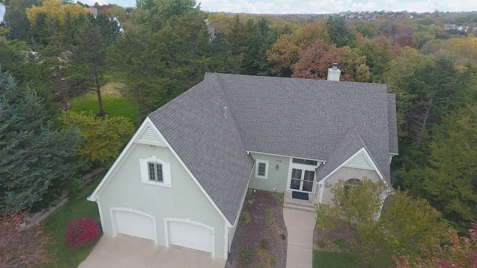 Independence, Missouri home with a new gray architectural shingle roof among fall trees