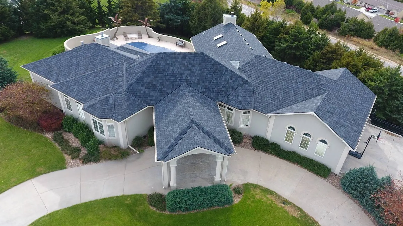 Large stucco home in Kansas City, Missouri with a new charcoal architectural shingle roof and circular driveway