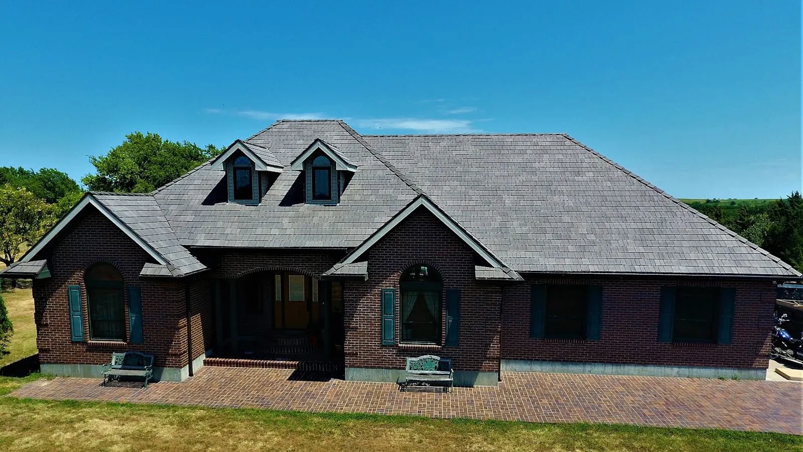 Brick home near Lansing, Kansas with a brand new architectural shingle roof under a clear blue sky