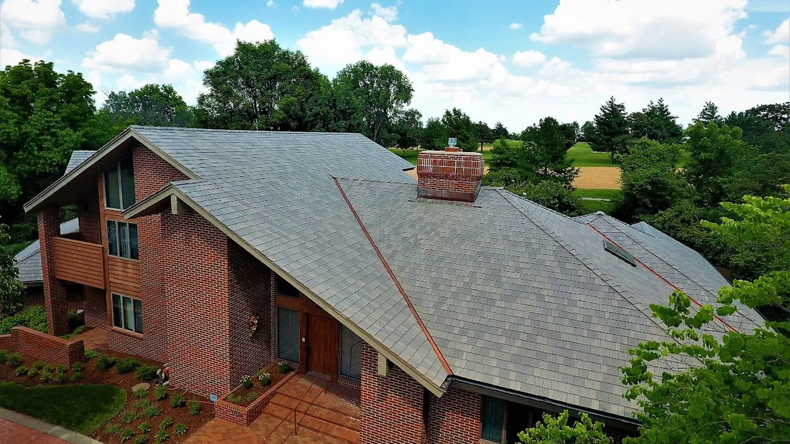 Aerial view of a brick home with a new slate style roof beside a golf course in Leavenworth, Kansas
