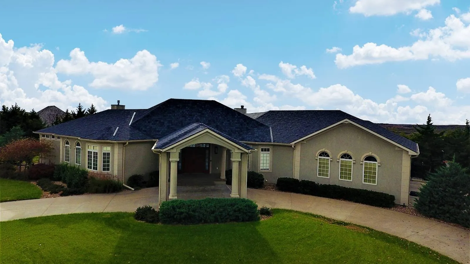 Lee's Summit, Missouri stucco ranch home with a new dark shingle roof and circular driveway