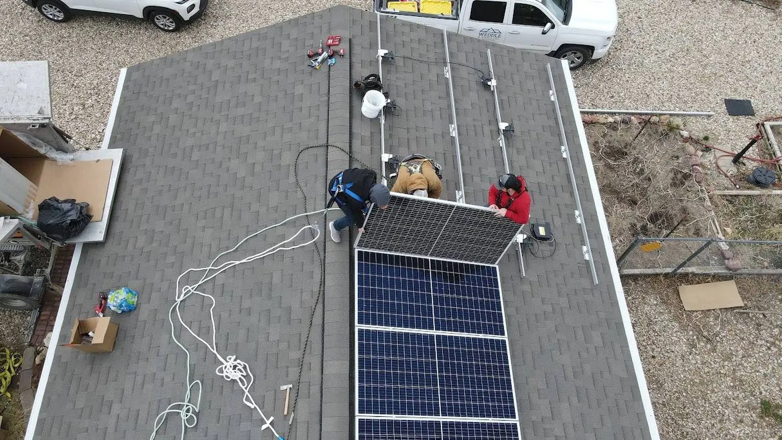 Aerial view of a crew installing solar panels on a shingle roof, serving Littleton, Colorado
