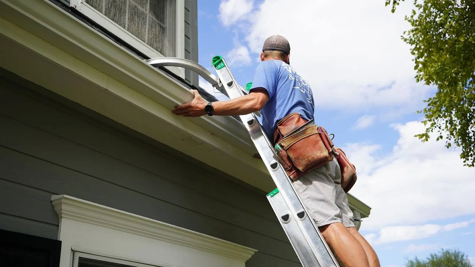 Weddle and Sons installer on a ladder securing a new gutter on a two story home, serving Lone Tree, Colorado