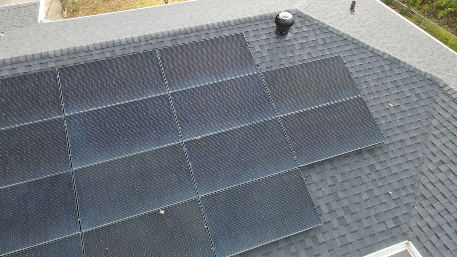 Aerial view of black solar panels on a freshly installed shingle roof at a Mission, Kansas home