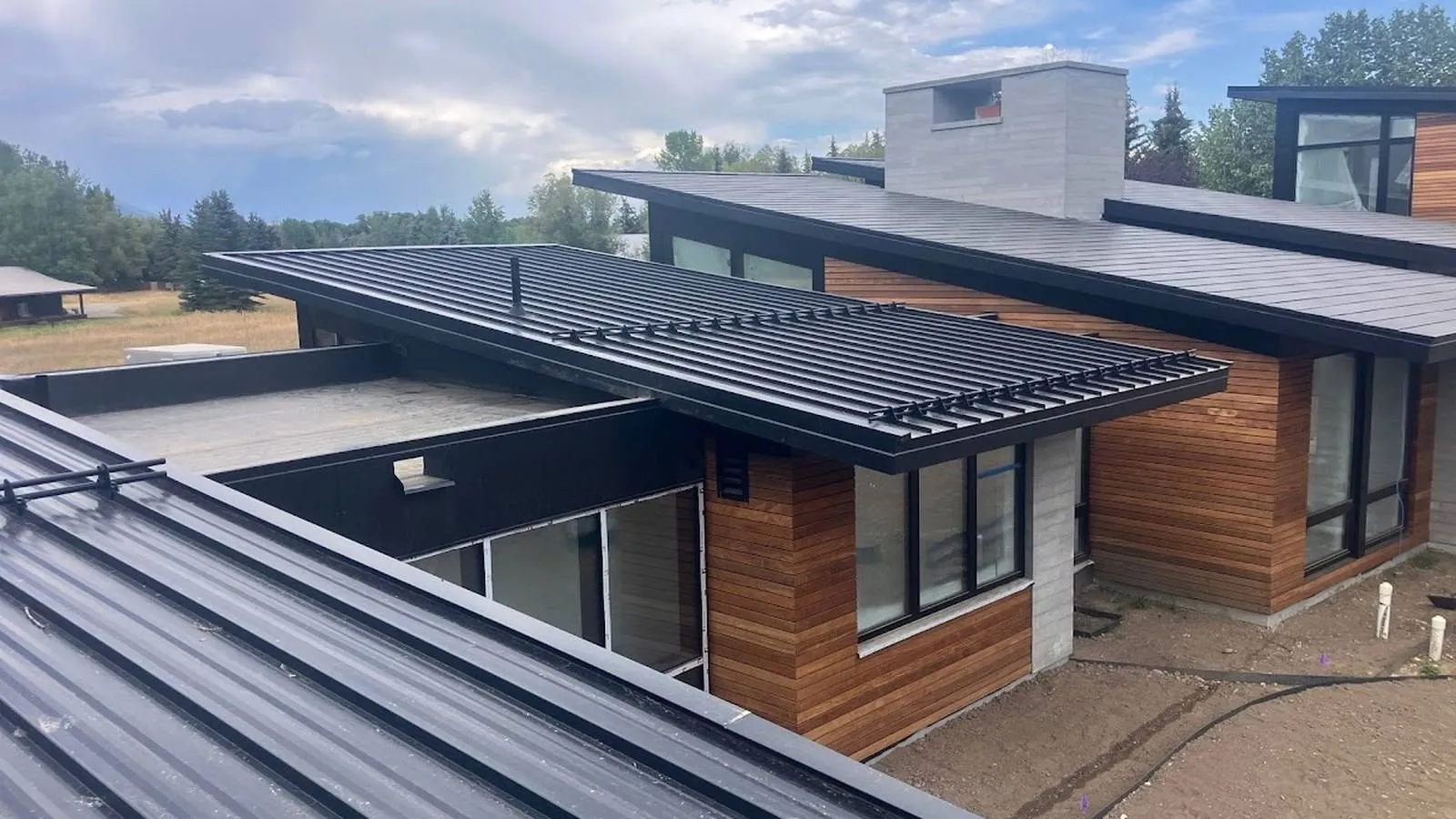 Modern mountain home near Nederland, Colorado with a black standing seam metal roof and snow retention guards installed by Weddle & Sons