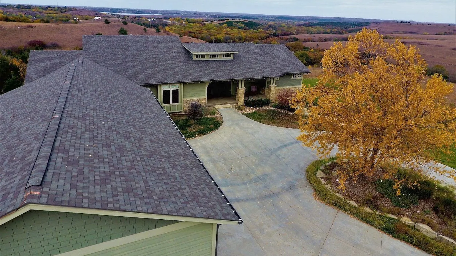 Aerial view of a craftsman home with a new shingle roof overlooking the rolling countryside near Osage City, Kansas