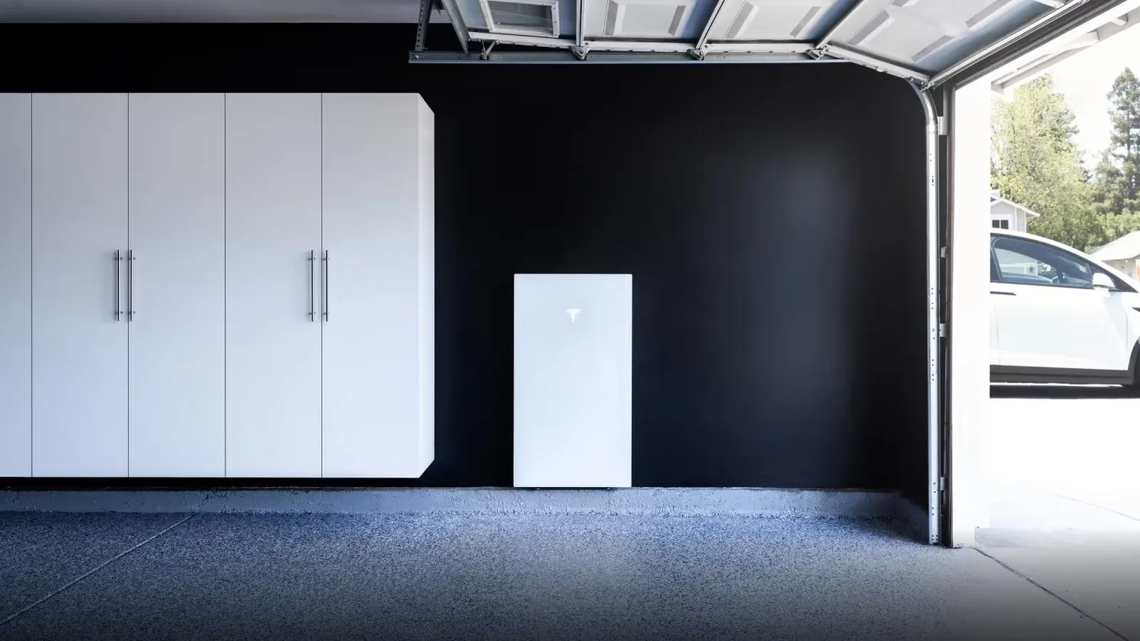 Tesla Powerwall home battery installed on a garage wall next to a parked car