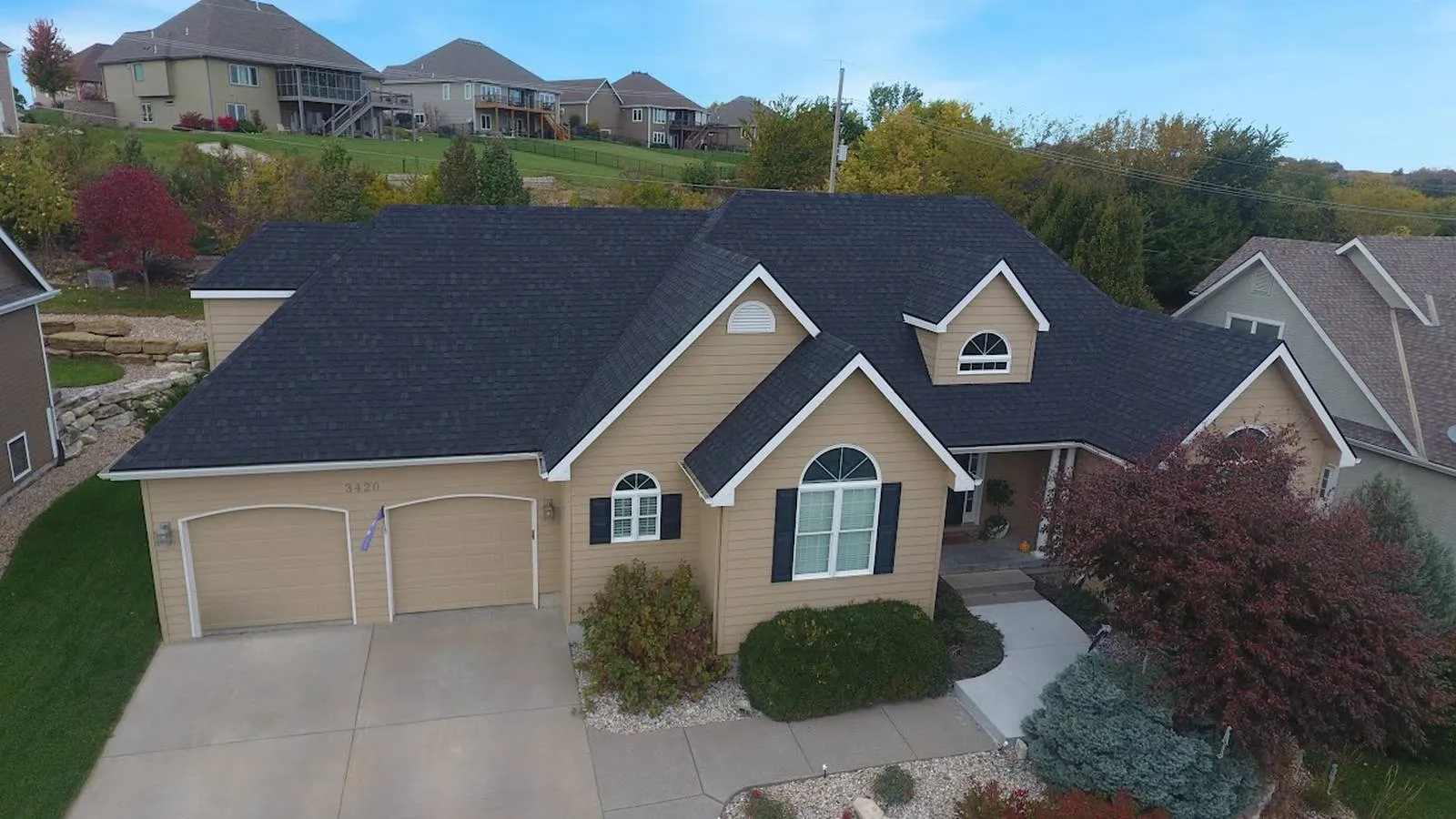 Raymore, Missouri home with a new black architectural shingle roof and stone landscaping in a hillside subdivision