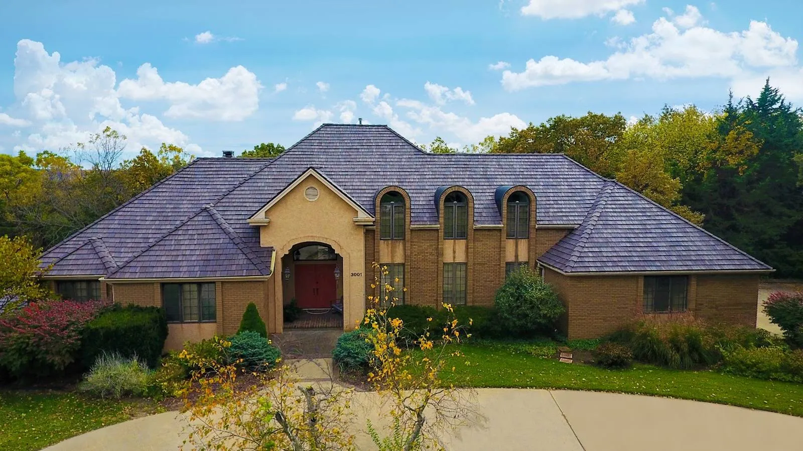 Brick two story home in Seneca, Kansas with a new synthetic slate roof and arched dormers