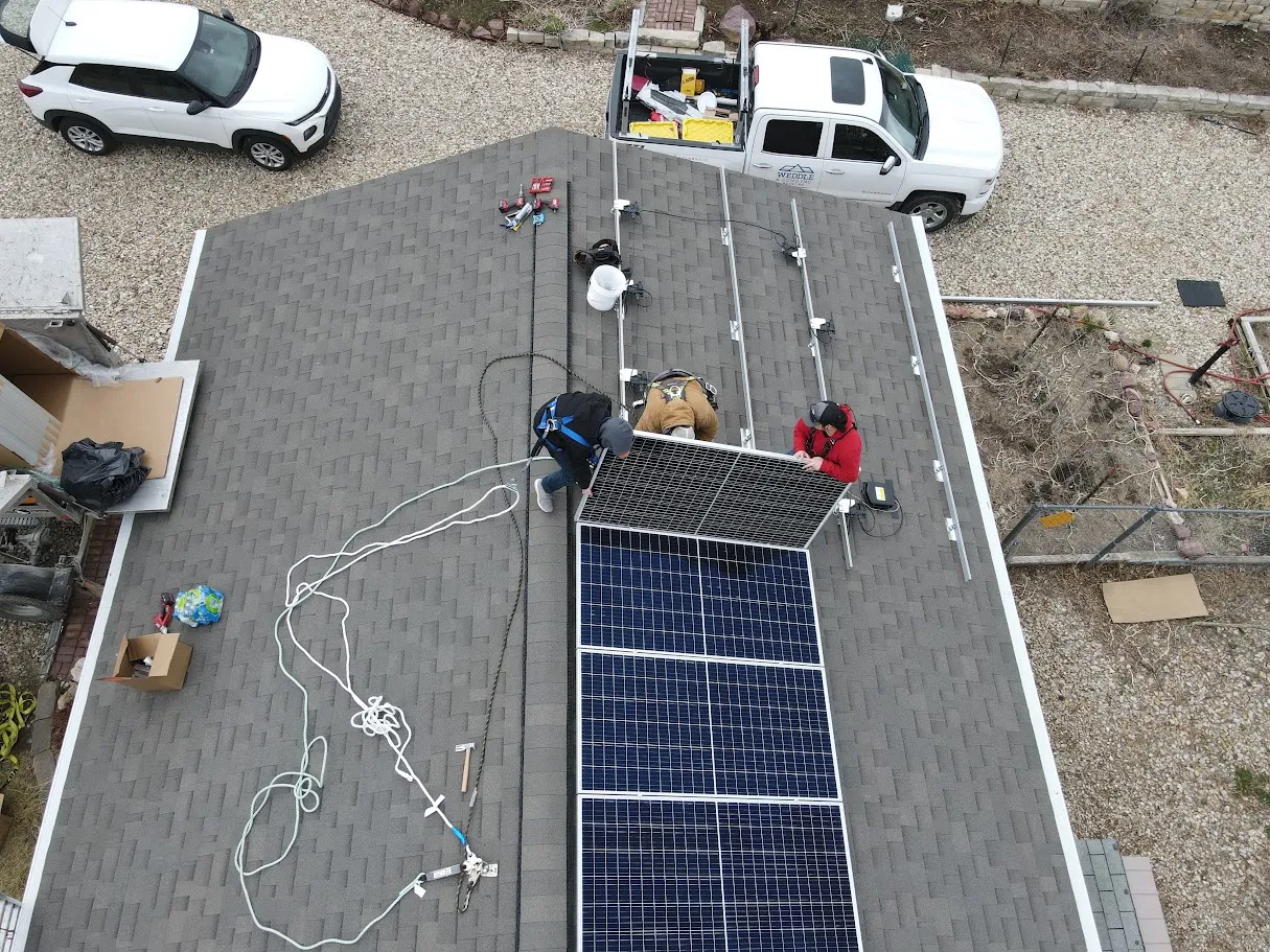 Aerial view of a Weddle and Sons crew installing solar panels on a shingle roof