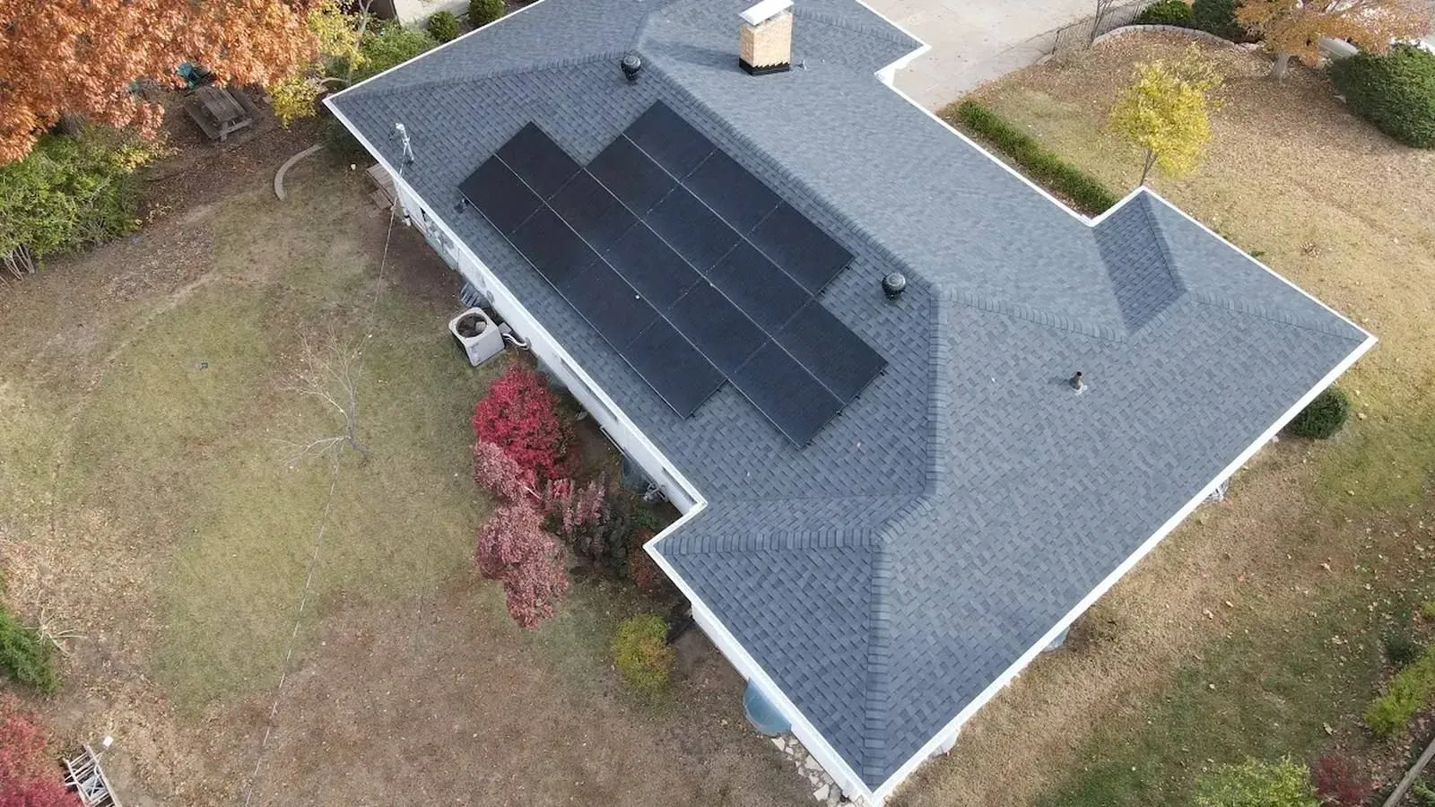 Aerial view of a Spring Hill, Kansas ranch home with a new shingle roof and black rooftop solar panels