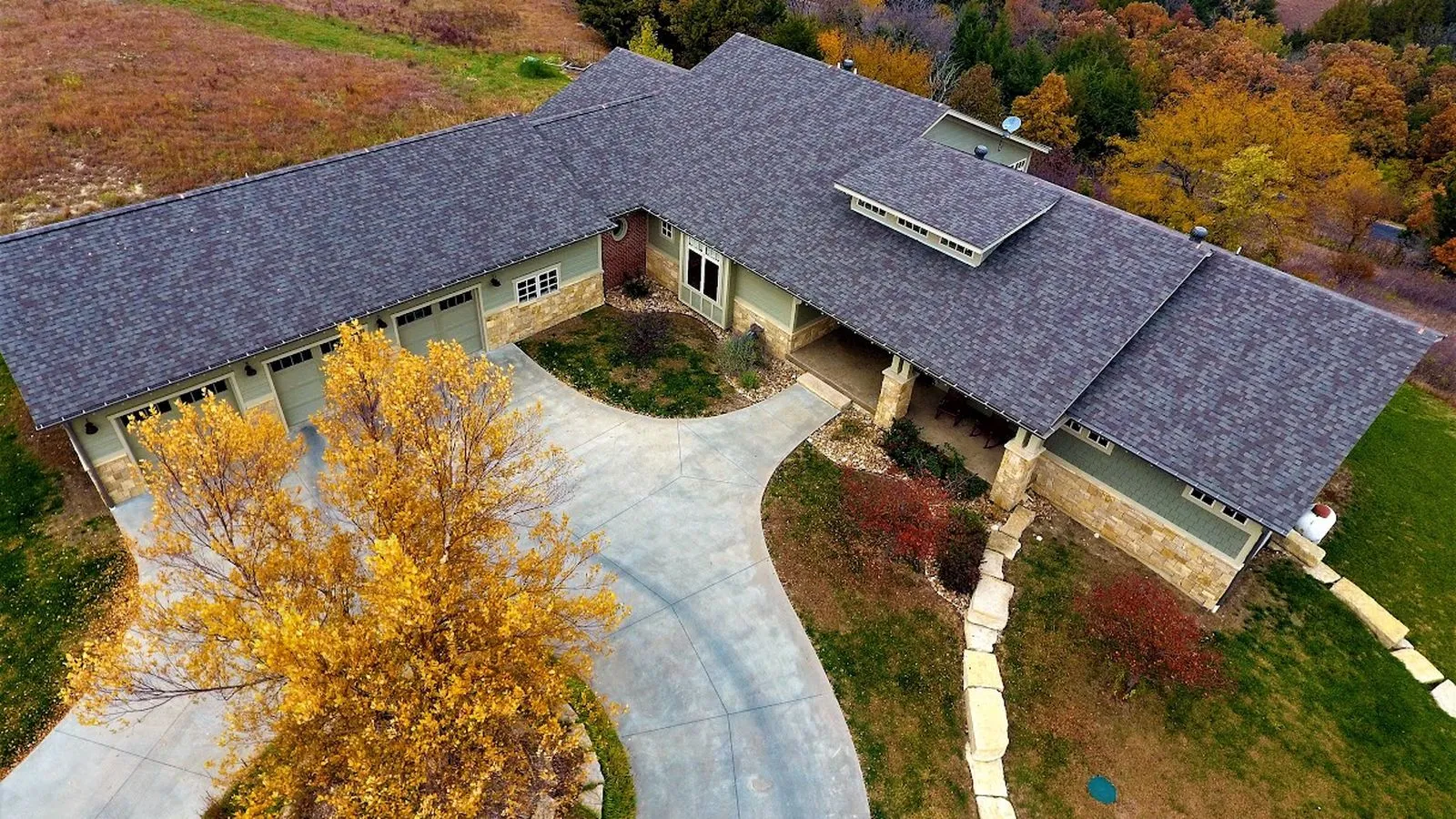 Aerial view of a craftsman home with a new shingle roof beside prairie hills in St. Marys, Kansas