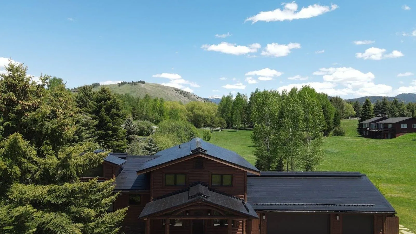 Mountain style home with a dark solar roof among evergreens, serving Superior, Colorado
