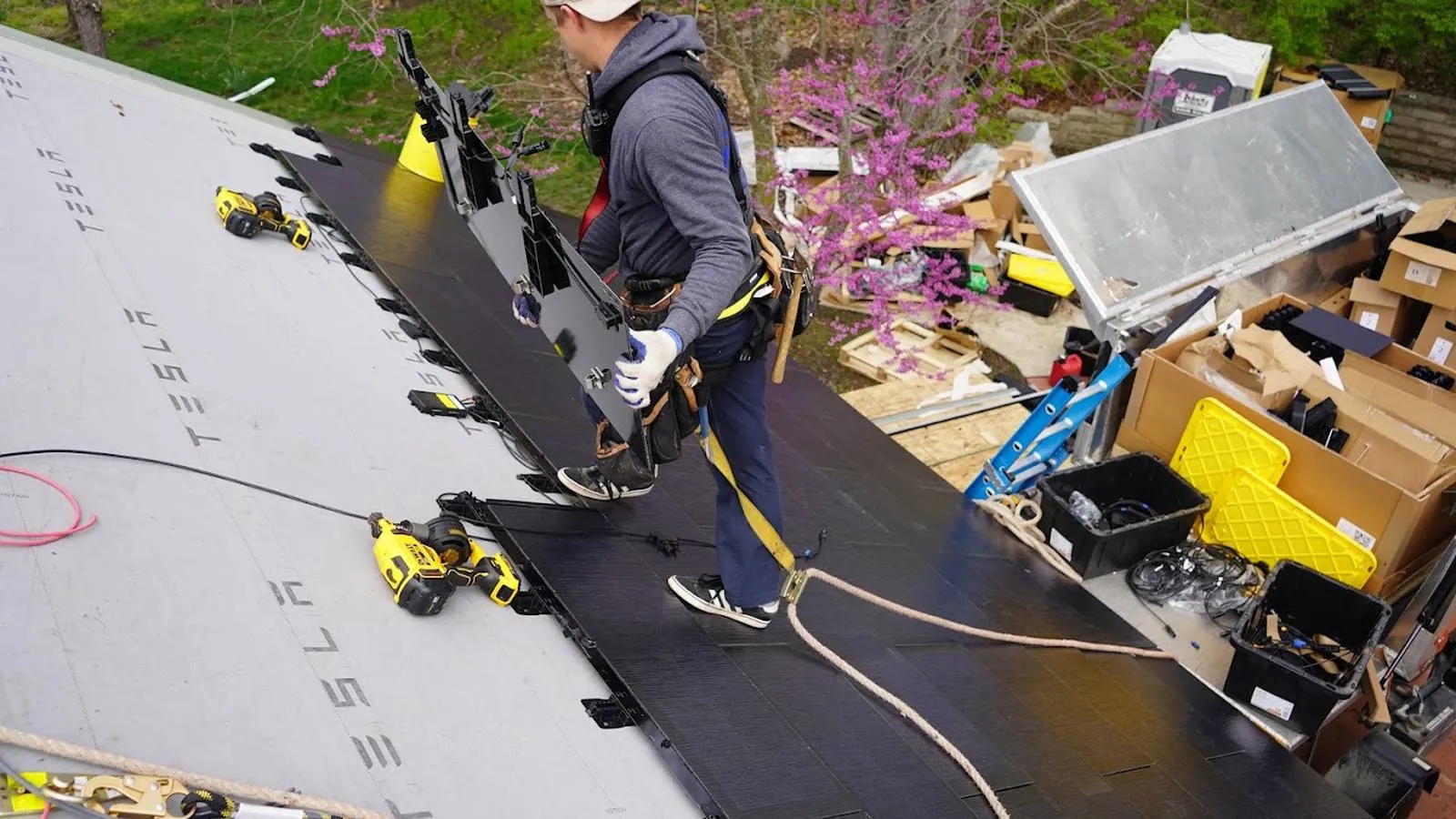Roofer carrying solar roof tiles during an installation in Syracuse, Nebraska