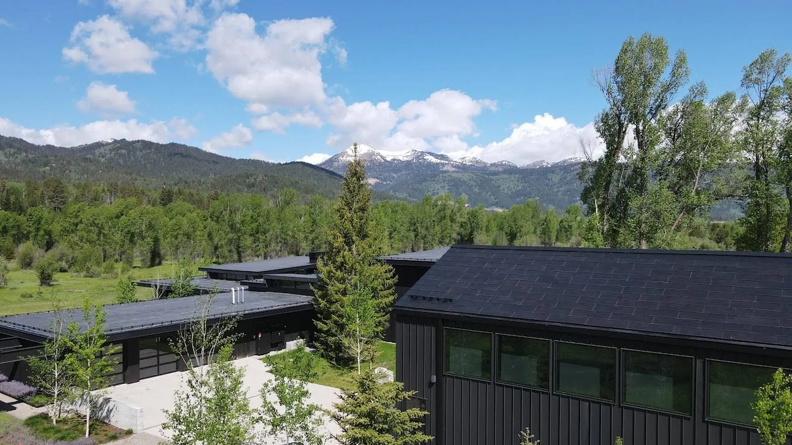 Tesla Solar Roof tiles on a modern black home with mountain views behind it
