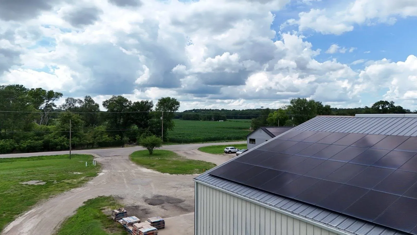 Solar panels installed on a metal roof outside Wahoo, Nebraska with cornfields and summer clouds in the background