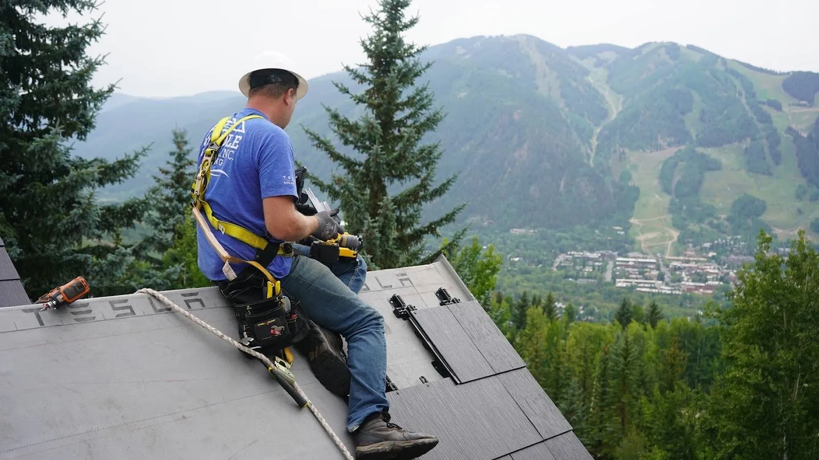 Weddle and Sons roofer inspecting a roof with mountain views behind him